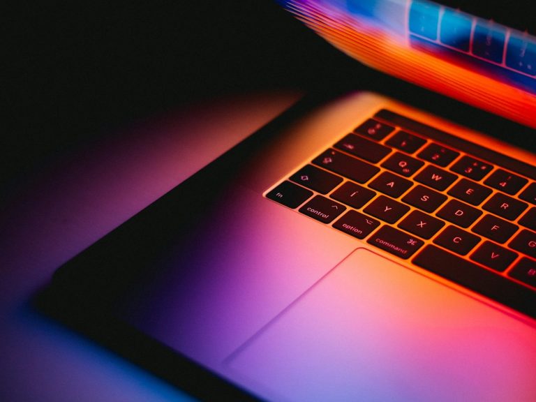 Laptop Ein Laptop mit leuchtender Tastatur und farbigem Hintergrund.